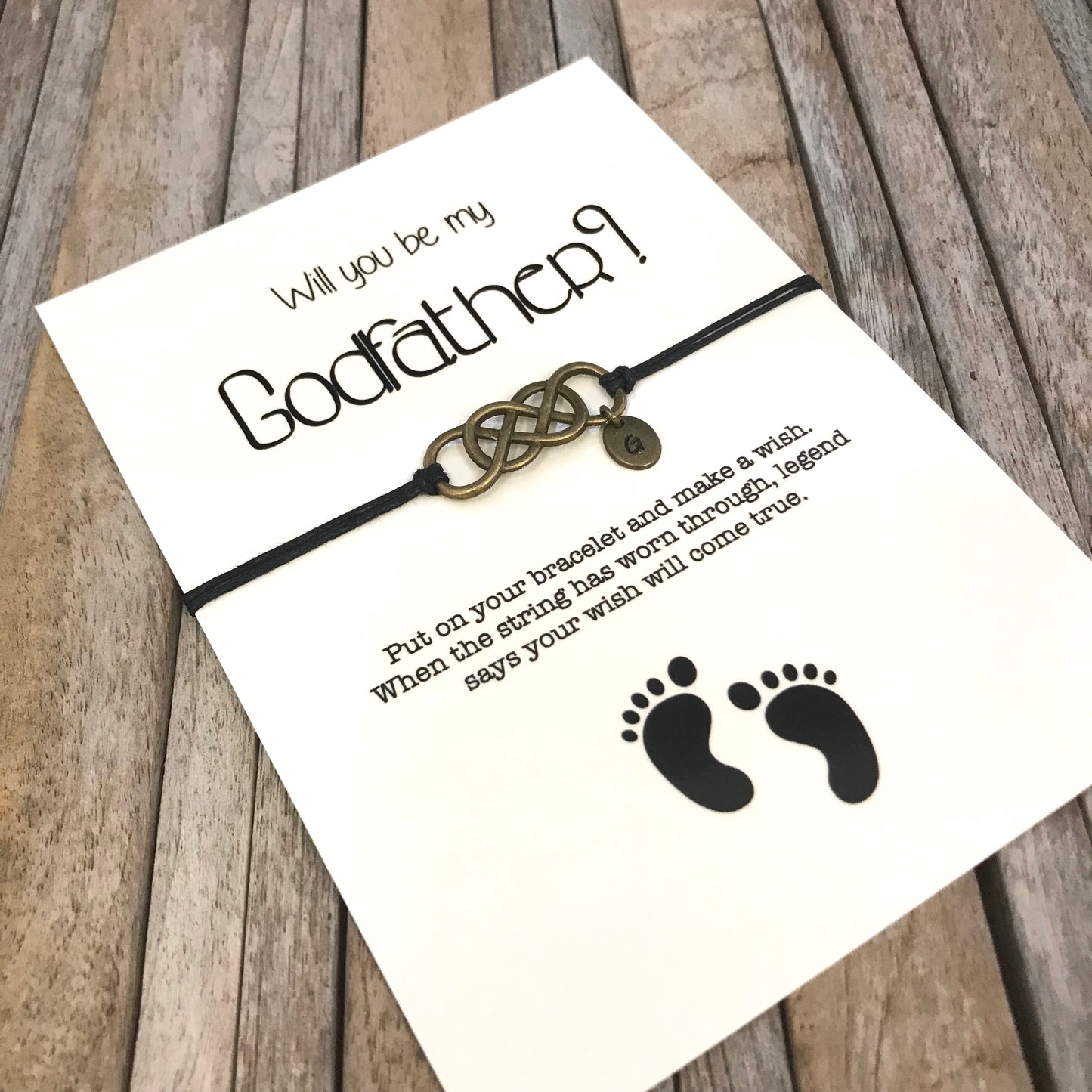 Godfather bracelet with customized initial charm, placed on "Will you be my godfather" proposal card
