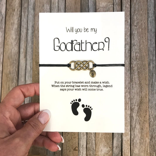 Godfather bracelet with customized initial charm, placed on "Will you be my godfather" proposal card